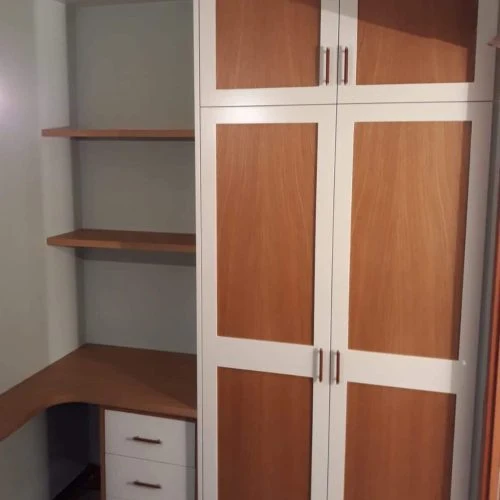 Armari de portes corredisses amb panells en dos tons, al costat d’una zona d’escriptori.