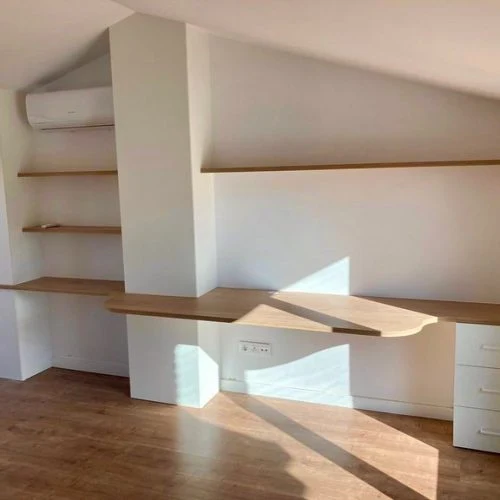 Prestatgeria oberta amb prestatges de diferents amplades, adaptada a un sostre inclinat.